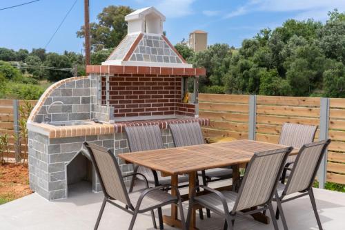 a patio with a brick fireplace and a wooden table and chairs at Blue Private Stone Villa Skala in Skala Kefalonias