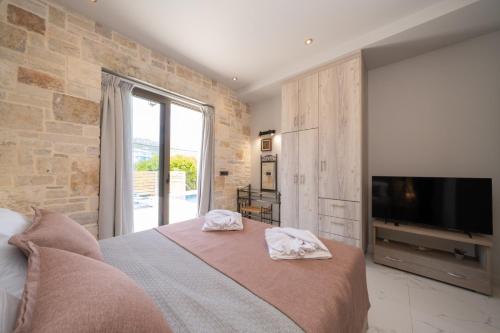 a bedroom with a large bed and a television at Blue Private Stone Villa Skala in Skala Kefalonias