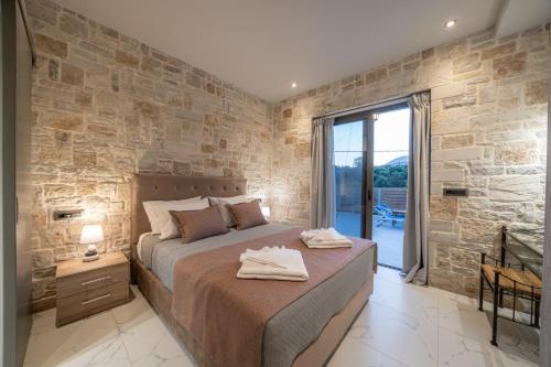 a bedroom with a large bed and a stone wall at Blue Private Stone Villa Skala in Skala Kefalonias