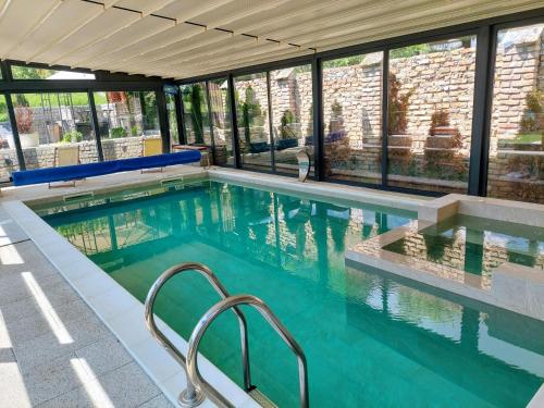 a swimming pool in a house with glass windows at Vila MP Banstol 4*- Brdež do, Fruška gora in Inđija
