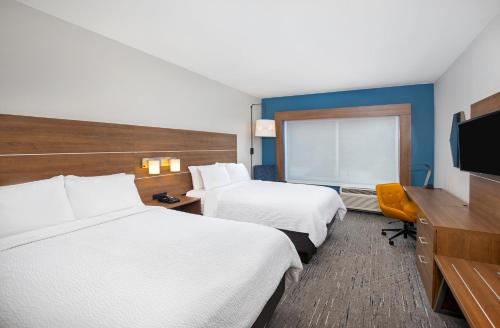 a hotel room with two beds and a flat screen tv at Holiday Inn Express & Suites - Carrollton West by IHG in Carrollton