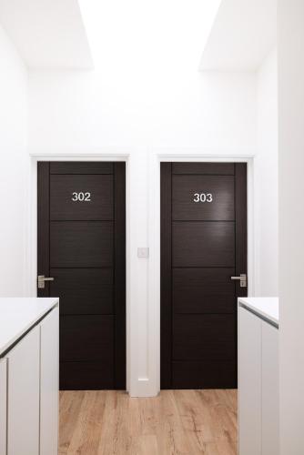 two black doors in a white room with wooden floors at Finsbury Rose in London