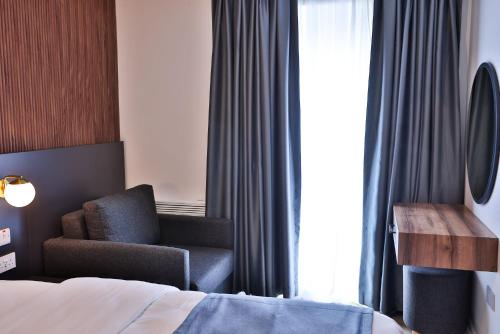 a bedroom with a bed and a chair next to a window at Finsbury Rose in London