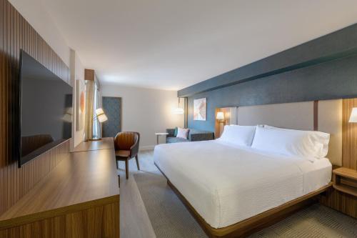 a hotel room with a large bed and a chair at Holiday Inn & Suites Winnipeg Downtown by IHG in Winnipeg