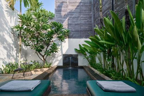 a pool in the middle of a garden with plants at The Embassy Angkor Resort & Spa in Siem Reap