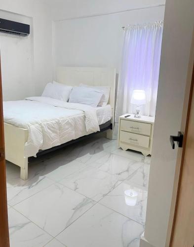 a white bedroom with a bed and a white tiled floor at Villa súper cómoda 3 habitaciones con piscina in Juan López