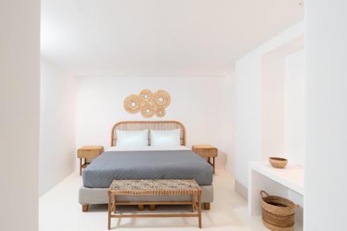 a white bedroom with a bed and a table at Frati Villas Beachfront in Perivolos