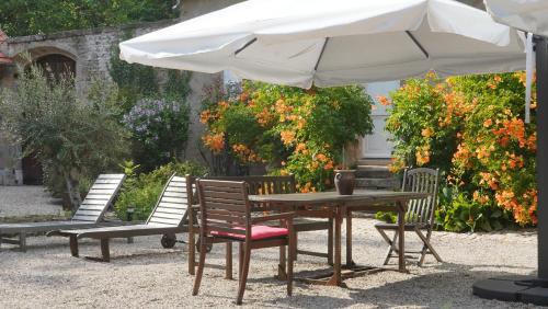 a table and chairs under a white umbrella at Domaine Les Bertrands in Couches
