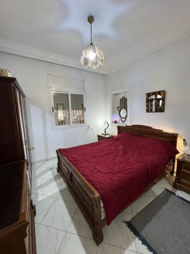a bedroom with a large bed with a red bedspread at Appart Campus in Ibn Khaldoun