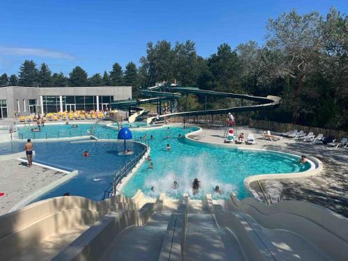 a large swimming pool with people in the water at Le Cottage de Belle Dune in Fort-Mahon-Plage