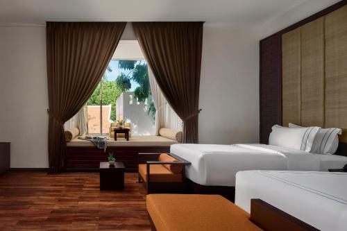 a hotel room with two beds and a window at The Embassy Angkor Resort & Spa in Siem Reap
