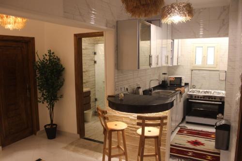 a kitchen with a sink and a counter with chairs at The Happy Home in Banī Ghālib