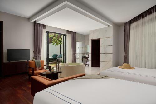 ein Hotelzimmer mit zwei Betten und einem Fernseher in der Unterkunft The Embassy Angkor Resort & Spa in Siem Reap