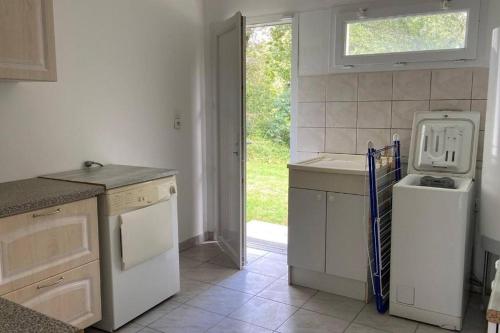 une cuisine avec évier et lave-vaisselle ainsi qu'une fenêtre dans l'établissement Escale Côte et Mer, à Clohars-Fouesnant