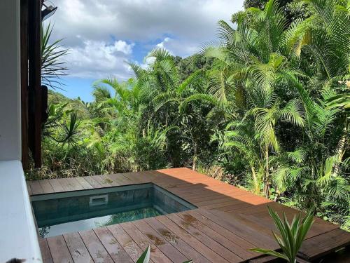 Cottage Ô Cœur de Bel Hâlé في سانت-روز: مسبح على سطح خشبي مع نخيل