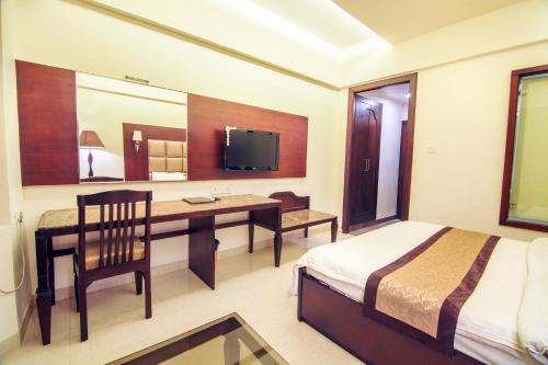 a bedroom with a desk and a bed and a television at Hotel Abhinandan in Mathura