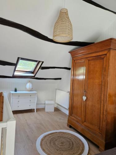 Cette chambre mansardée comprend une armoire en bois et une fenêtre. dans l'établissement Le Courtil de Grammont, à La Celle-sous-Gouzon