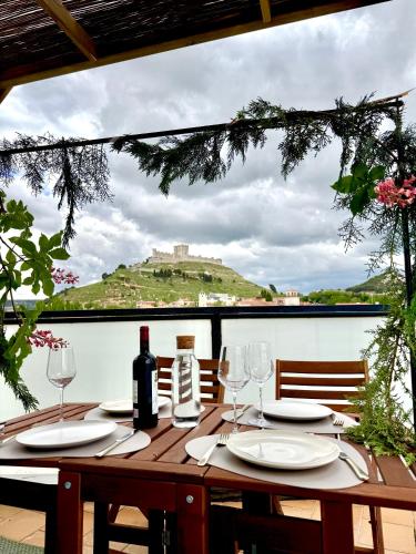 a wooden table with wine glasses and a view of a hill at Casa de la luz in Peñafiel