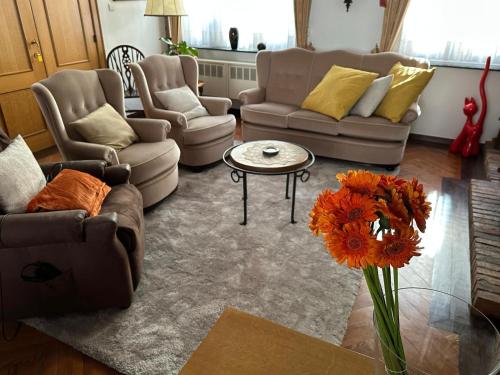 a living room with couches and a table and flowers at In De Wulf in Ypres