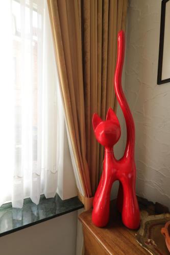 a red statue of a cat sitting on a window sill at In De Wulf in Ypres
