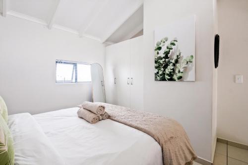 Un dormitorio blanco con una cama con una manta. en Peaceful Fourways Loft Apartment, en Sandton
