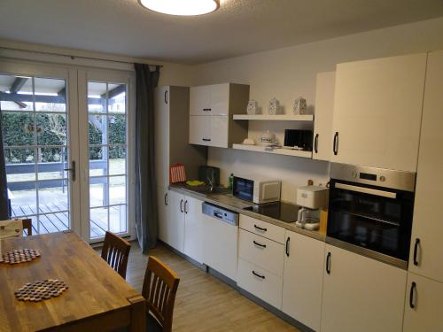 a kitchen with white cabinets and a table and a dining room at Ferienwohnung Sonnenaufgang im Ruppiner Land in Kränzlin