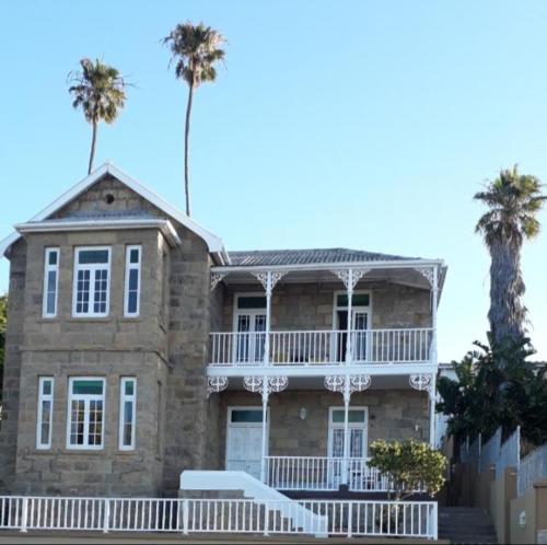 a large stone house with palm trees in the background at Twin Palms Accommodations in Mossel Bay