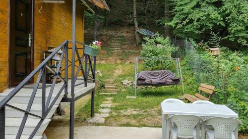 a porch with a white table and chairs and a bed at Cottage in Tskhvarichamia forest in Mtskheta