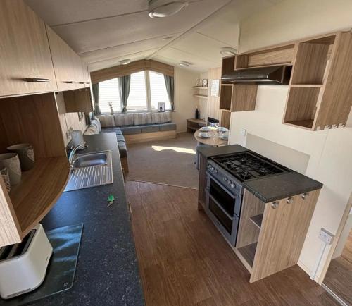 a kitchen with a stove and a living room at Seaside Caravan in Leisure Park with WiFi & Parking with decking 2 bedrooms in Rhyl