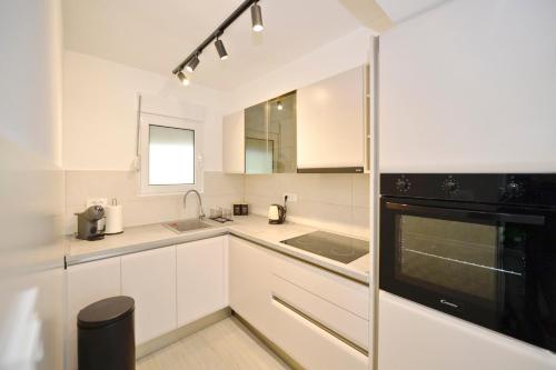 a kitchen with white cabinets and a black appliance at SEA VIEW apartment 2km from the Old Town of Kotor in Dobrota