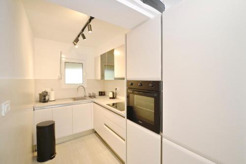 a kitchen with white cabinets and a black appliance at SEA VIEW apartment 2km from the Old Town of Kotor in Dobrota