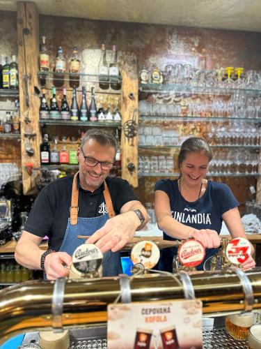a man and a woman behind a counter in a bar at Pension U Studny in Harrachov