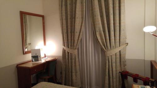 a room with a curtain and a table and a mirror at Terra Umbra Hotel in Narni