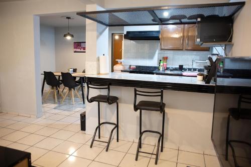a kitchen with a counter with stools in it at Departamento Maestro in León