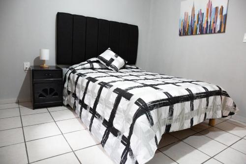 a bedroom with a bed with a black and white comforter at Departamento Maestro in León