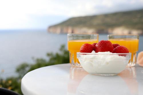 two glasses of orange juice and a bowl of strawberries at Panorama Rooms in Pirgos Dhirou