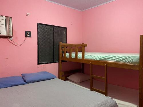 zwei Etagenbetten in einem Zimmer mit rosa Wänden in der Unterkunft Residencial Romulo Casa in Manaus