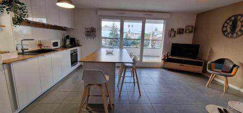 a kitchen with white cabinets and a table and chairs at Le Cocon in Thonon-les-Bains