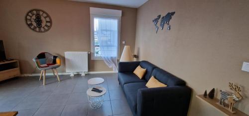 a living room with a blue couch and a clock at Le Cocon in Thonon-les-Bains