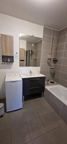 a bathroom with a sink and a tub and a mirror at Le Cocon in Thonon-les-Bains