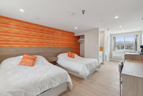 Un dormitorio con dos camas y una pared naranja. en The Voyager, en Old Orchard Beach