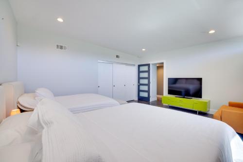 a bedroom with a white bed and a television at 3 Mi to Strip Mid-Century Gem with Hot Tub in Vegas in Las Vegas