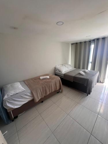 Un dormitorio con dos camas y una ventana. en Apartamento na Orla da Praia Grande para até 6 pessoas - Arraial do Cabo, en Arraial do Cabo