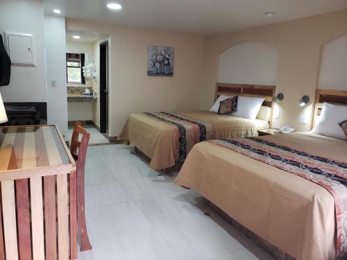 a hotel room with two beds and a table at La Villa de Zaragoza in Tijuana