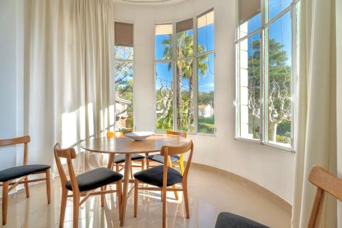 une salle à manger avec une table, des chaises et des fenêtres dans l'établissement Appartement unique - 6 personnes - Clim Terrasse Parking Plages, à Saint-Raphaël