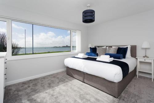 a bedroom with a large bed and a large window at Castle View - 2 Bed Stylish Coastal Port Solent Retreat with Views! Parking, Sleeps 6 - By Blue Puffin Stays in Portsmouth
