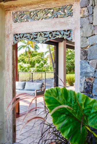 an open door to a patio with a chair on a porch at La Villa Paille en Queue in Saint-Gilles les Bains