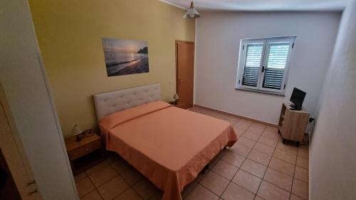 a small bedroom with a bed and a window at Orange Villa in Capo Vaticano
