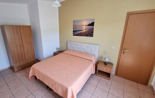 a small bedroom with a bed and a picture of the ocean at Orange Villa in Capo Vaticano