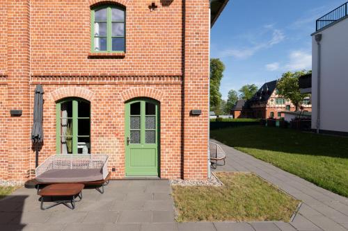 a brick building with a green door and benches at Müritzperle am Müritzufer Klink in Klink
